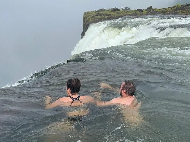 A man smiling for the camera while standing in Devil's Pool at Victoria Falls