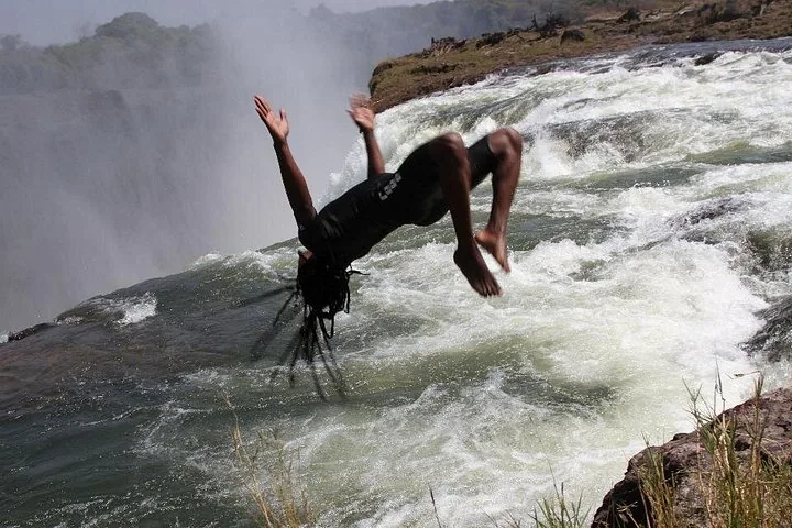 People looking over the edge from Devil's Pool at the misty Victoria Falls