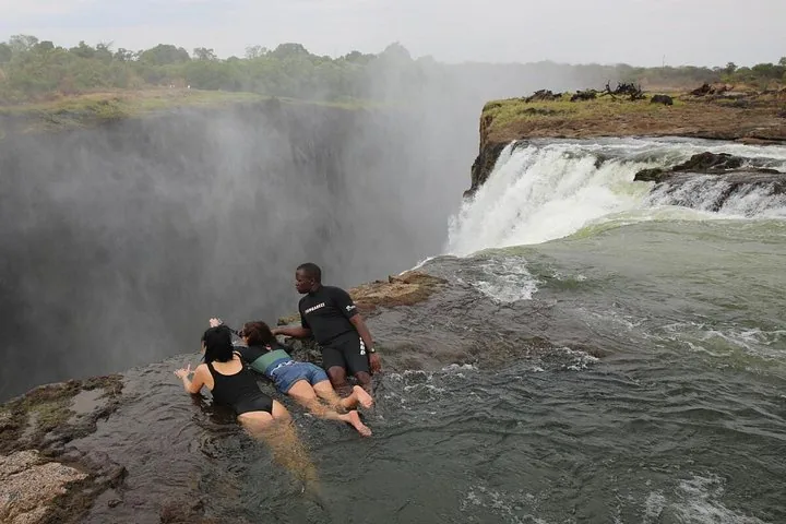 Tourists lying in the water at the edge of Devil's Pool, Victoria Falls